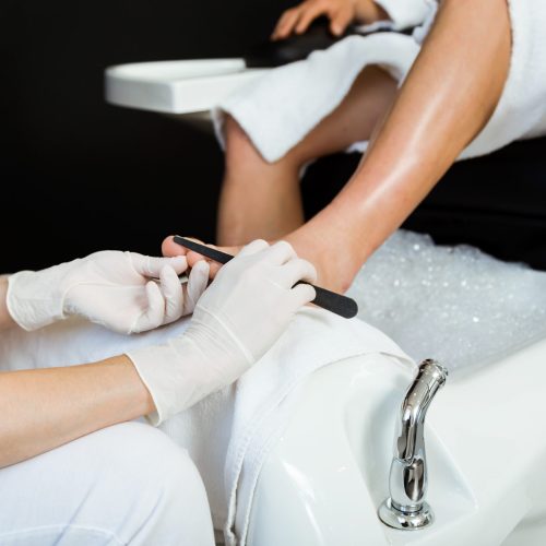 Portrait of young man doing pedicure in salon. Beauty concept.
